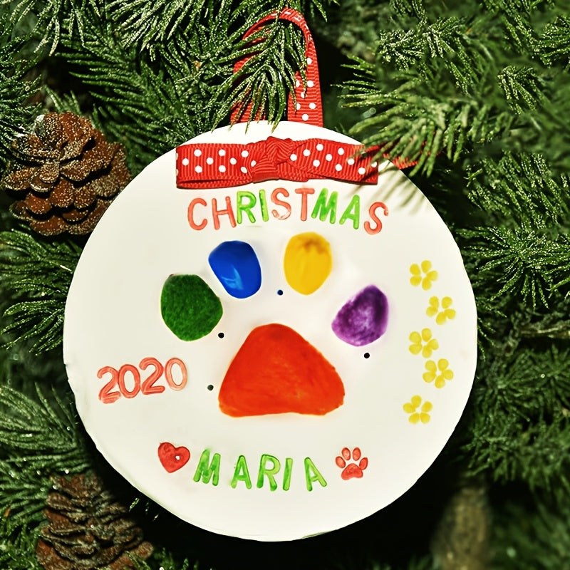 Decorative Christmas ornament with colorful paw prints and '2020 Maria' text, hanging on a tree.