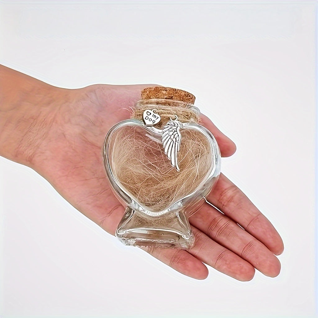 Heart-shaped glass jar with angel wing charm and hair, held in a hand against a white background