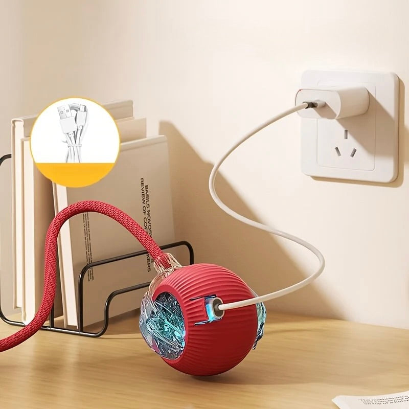 Red ball-shaped device with a cable plugged into an outlet on a wooden surface.